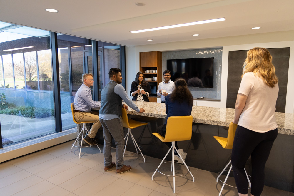 A group of diverse employees standing and sitting around a countertop