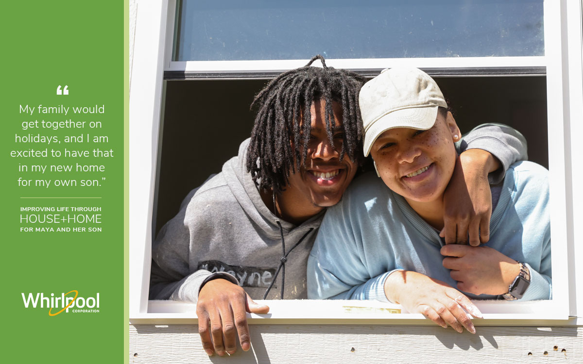 New Habitat homeowner Maya and her son smile with their heads out the window of their new home